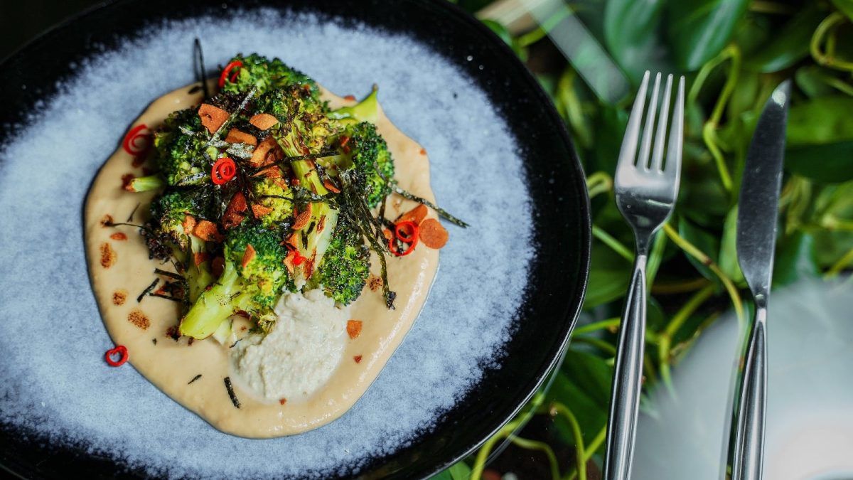 Ein hellblauer Teller mit geröstetem Brokkoli auf Miso-Hummus.