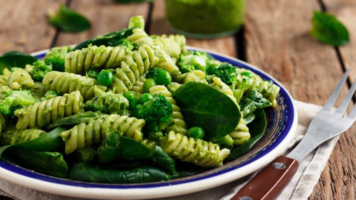 Ein Teller Green Goddess Nudelsalat mit Erbsen und Babyspinat, daneben eine Gabel.