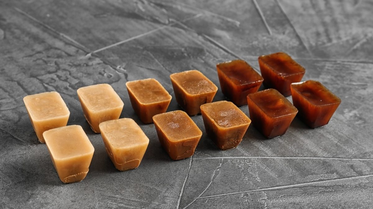 Eine Reihe an Kaffee-Eiswürfeln auf einem grauen Tisch.