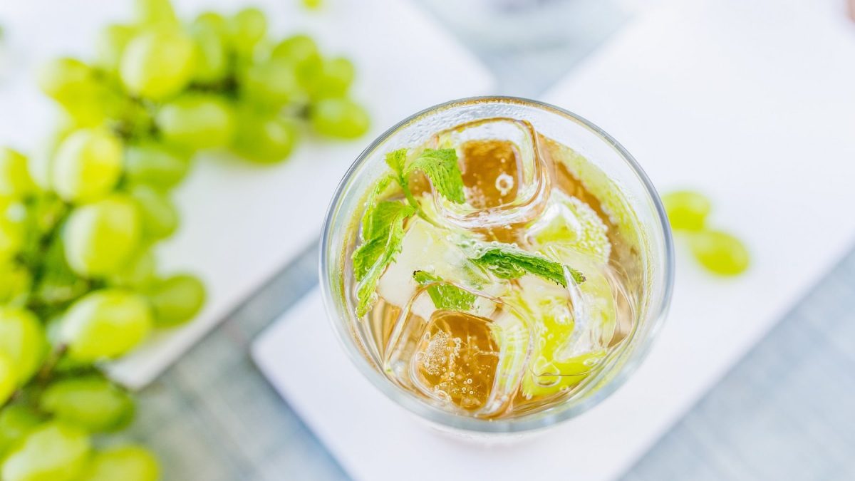 Ein Glas Lillet Elite auf hellem Untergrund mit Weintrauben direkt von oben fotografiert,