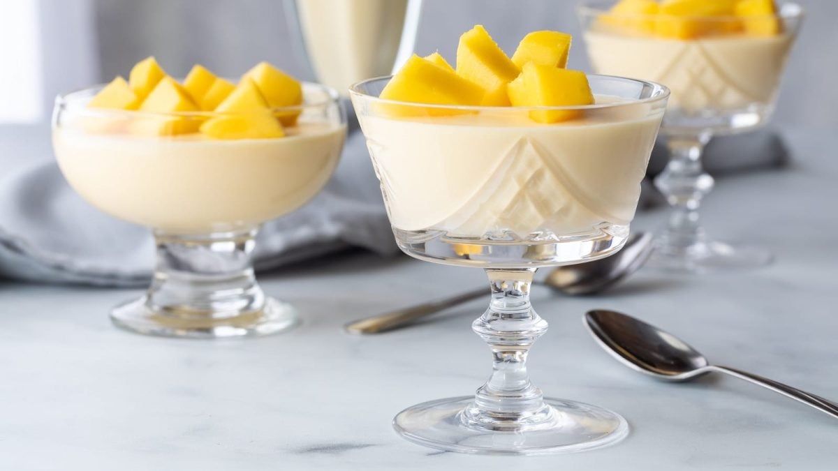 Drei Gläser mit Mango Mousse auf einem hellen Tisch.