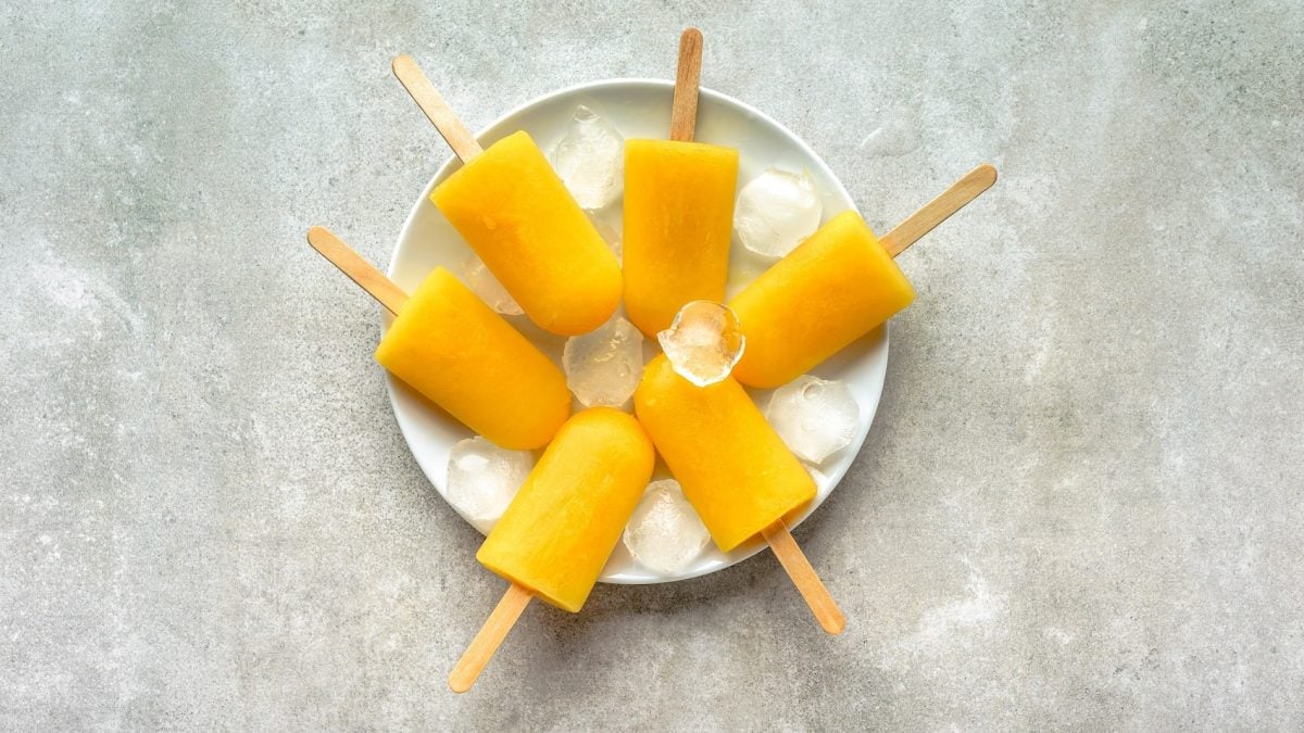 Ein Teller mit Mango Popsicles auf einem Steinuntergrund.
