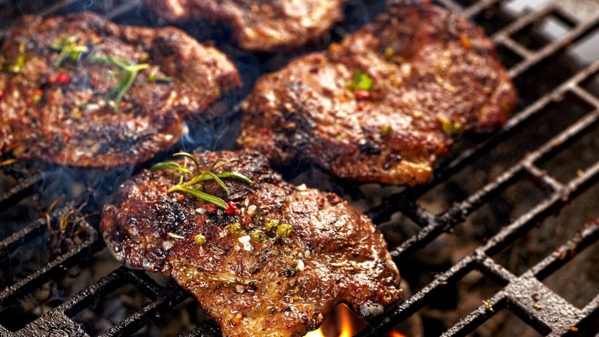 Gegrillte Nackensteaks mit Paprikamarinade auf Grillrost. Draufsicht.