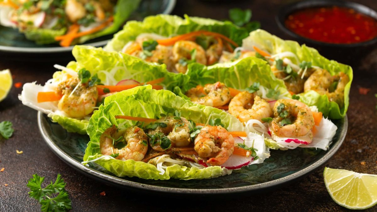 Ein dunkler Teller mit den Salat-Wraps gefüllt mit Garnelen und Reisnudeln.