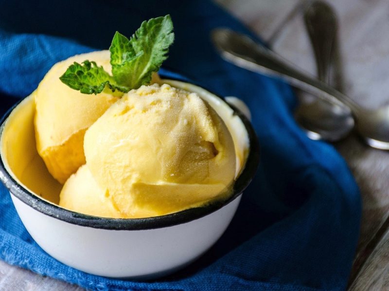Eine weiße Schüssel mit Mango-Eis auf einem blauen Tuch.