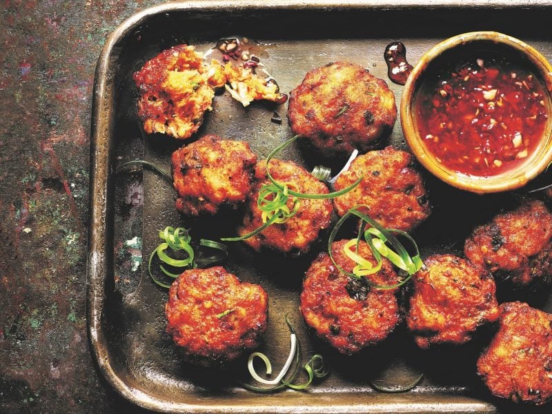 Mehrere Fischkroketten auf einem dunklen Teller mit Sweet-Chili-Sauce.