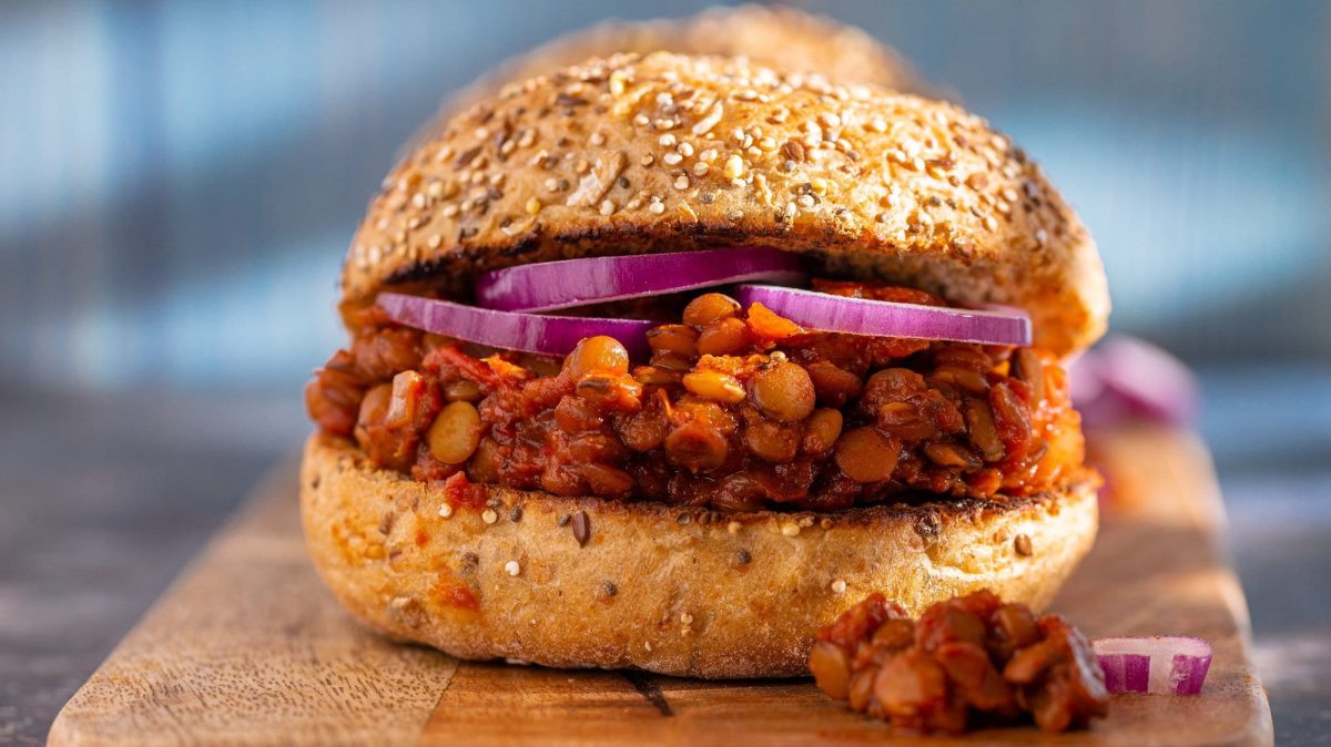 Ein veganer Sloppy Joes mit Linsen und roten Zwiebeln auf einem Brett.