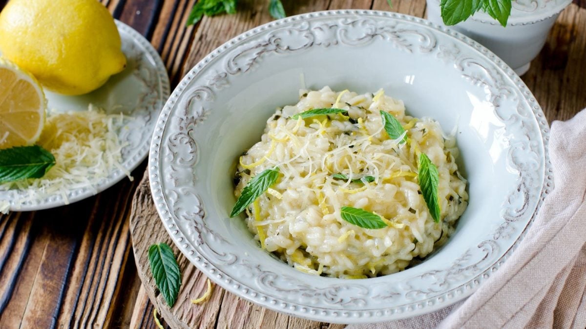 Ein Teller mit Zitronen-Risotto mit Minze auf einem Holztisch.