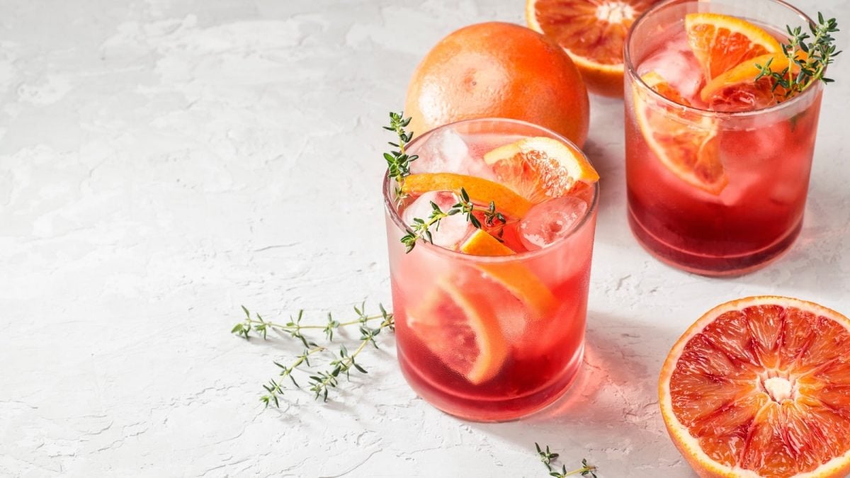 Ein Glas mit Campari Spritz auf einem hellen Hintergrund.