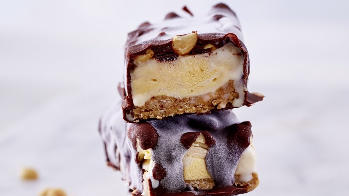 Ein drei-schichtiger Frozen Peanut-Caramel-Bar vor einem weißen Hintergrund.