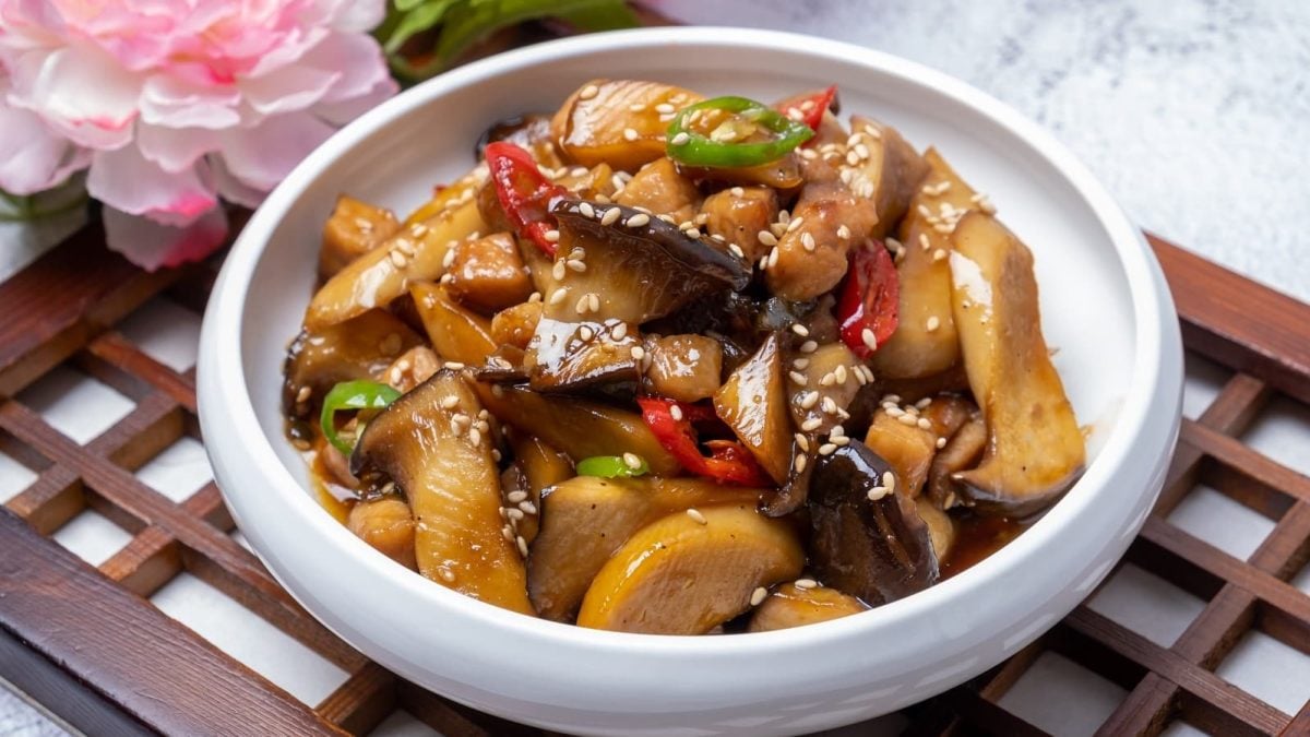 Eine weiße Schüssel mit gebratenen Kräuterseitlingen in Knoblauchsauce.