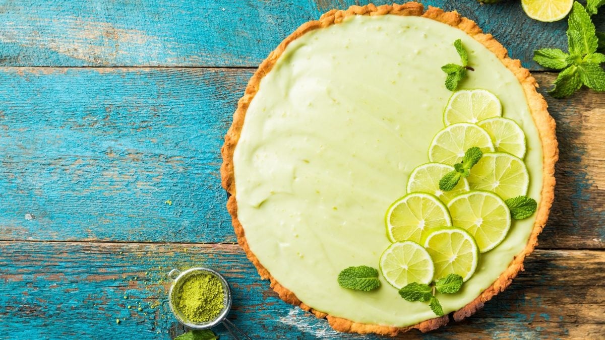 Ein Key Lime Pie mit Matcha auf einem rustikalen Holztisch, der leicht blau lackiert ist.