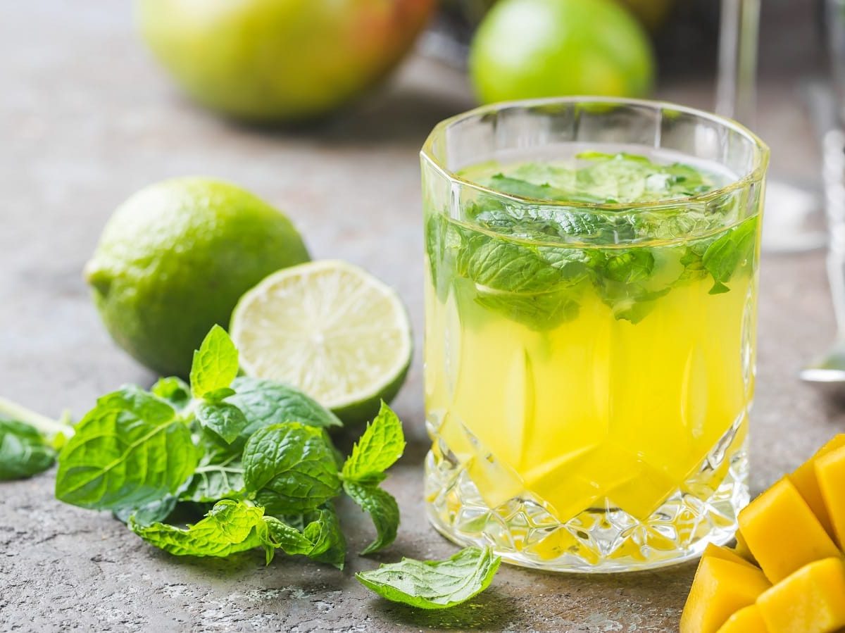 Ein Glas Mango Mojito auf einem grauen Tisch.