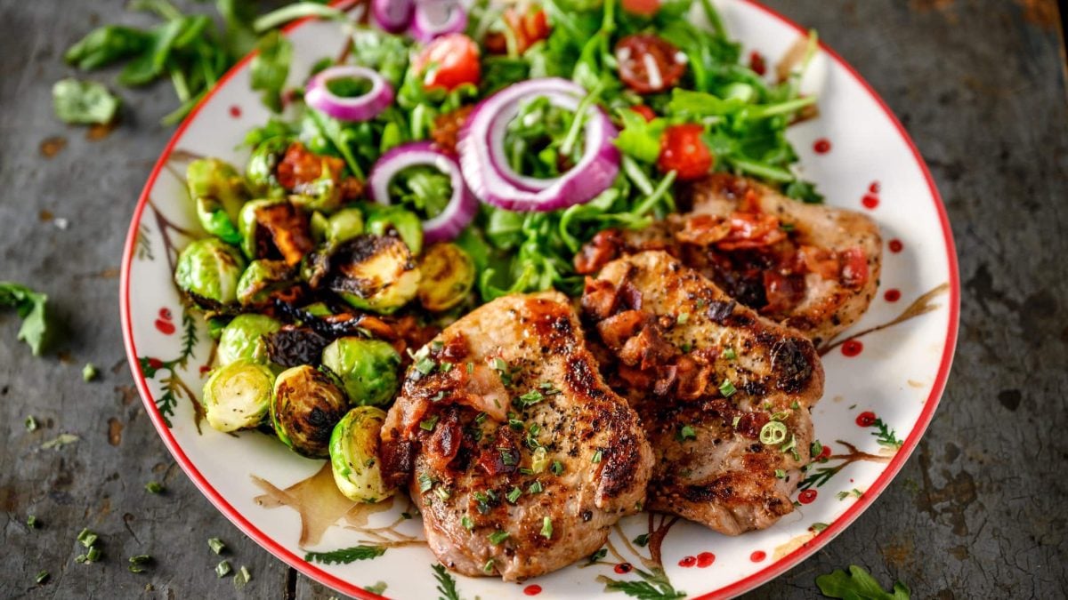 Selbst gemachte Minutensteaks nach Gyros-Art vom Grill drei gegrillte Minutensteaks Gyros mit Salat und Rosenkohl auf Teller auf dunklem Holz. Draufsicht.