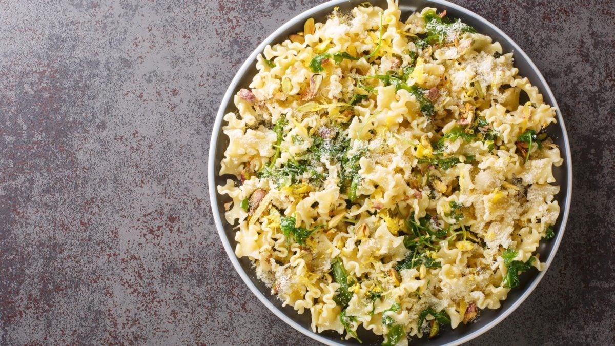 Draufsicht: eine runde Schüssel Pasta con’ pistacchio steht auf einem grau meliertem Untergrund.