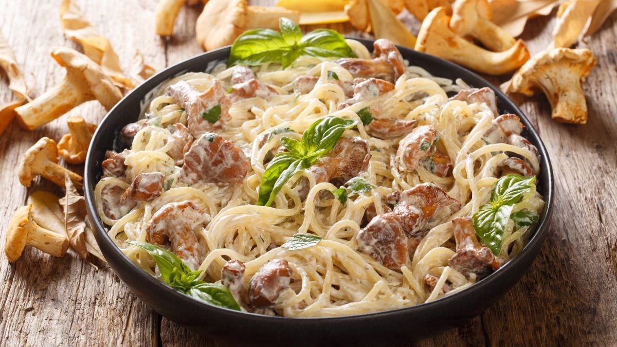 Eine gusseiserne Pfanne mit den Spaghetti mit Pfifferlingen und Knoblauchsauce.
