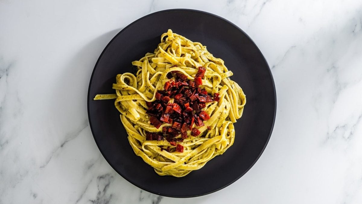 Pasta mit Rotebetespeck auf einem schwarzen Teller.