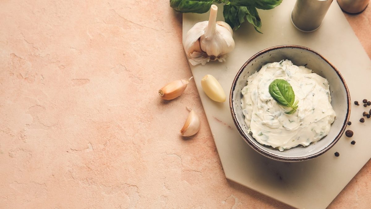 Eine Schüssel mit Ziegenkäse-Butter auf einem Holzbrett.