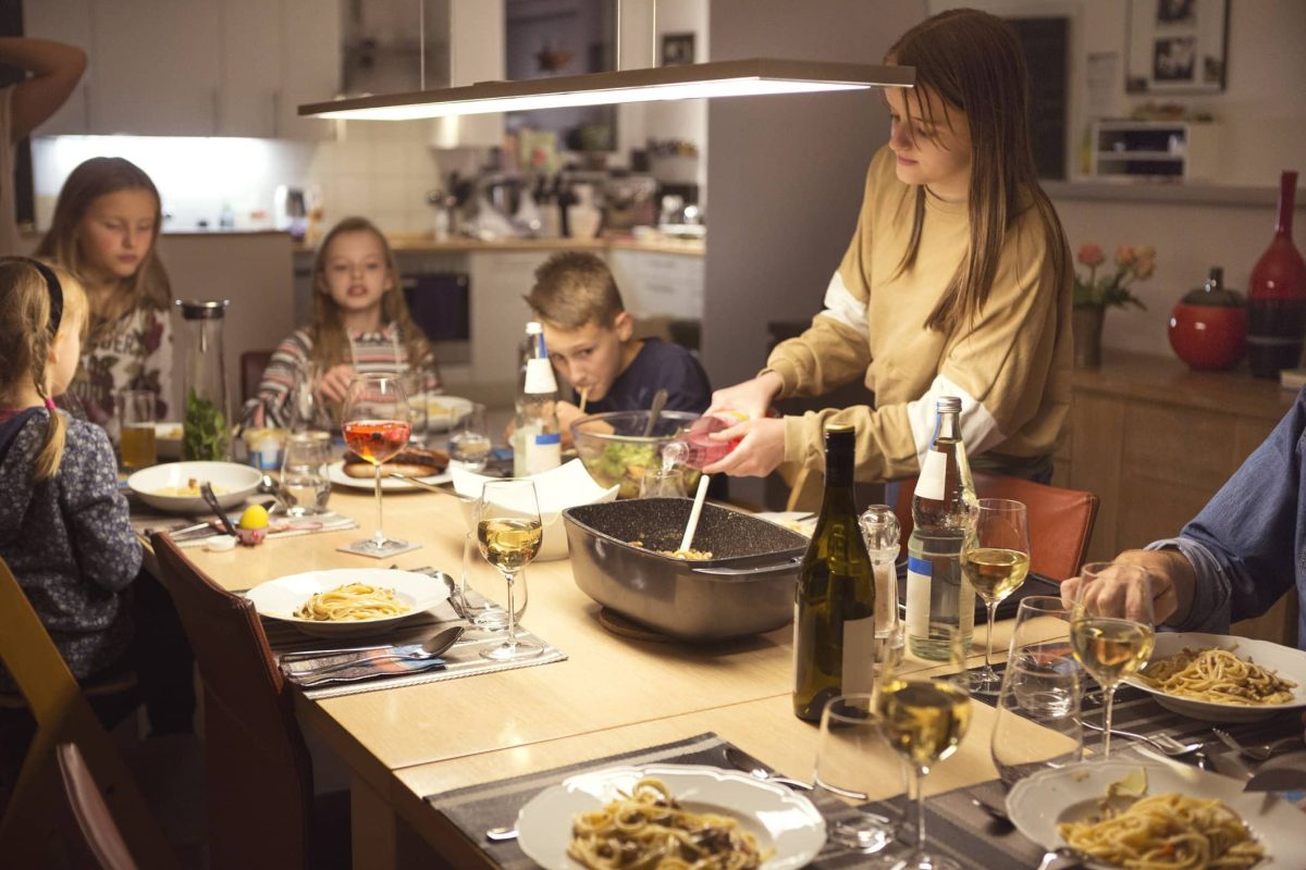 Eine Familie in der Wohnküche. Auf den Tisch stehen speisen und sie essen gemeinsam.