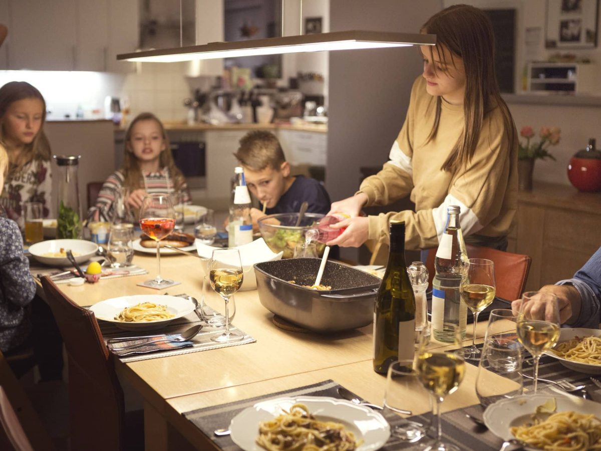 Eine Familie in der Wohnküche. Auf den Tisch stehen speisen und sie essen gemeinsam.