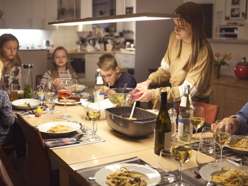 Eine Familie in der Wohnküche. Auf den Tisch stehen speisen und sie essen gemeinsam.