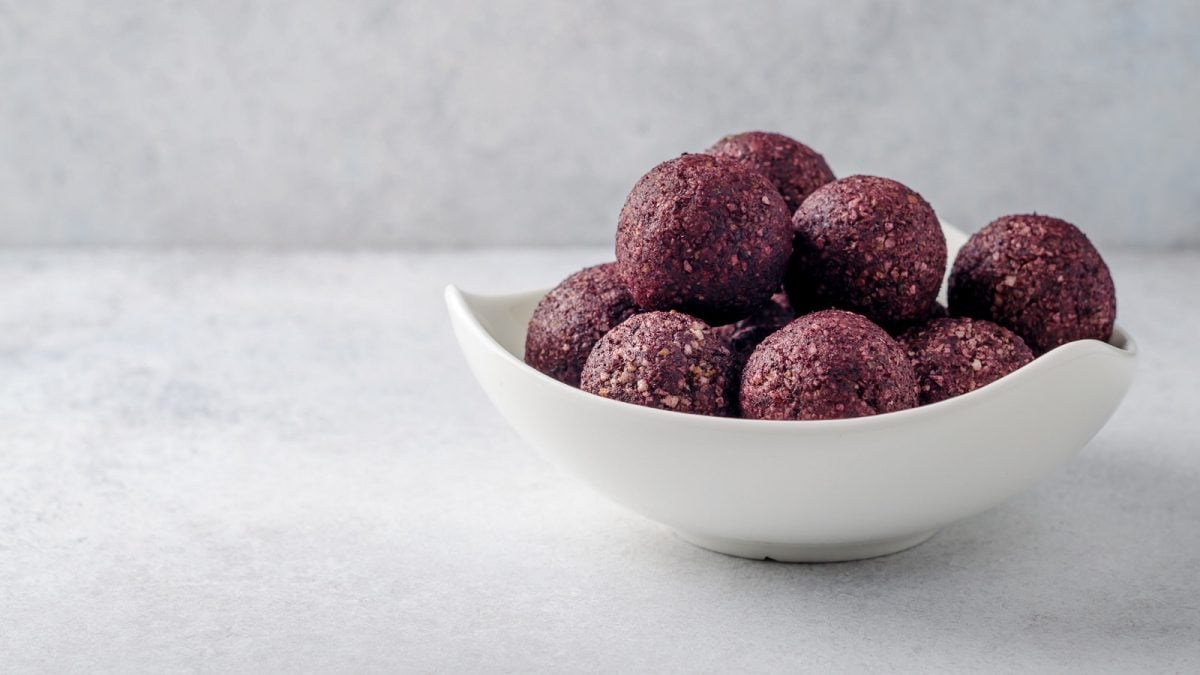Eine weiße Schale mit Acai Energy Balls auf einem weißen Grund.