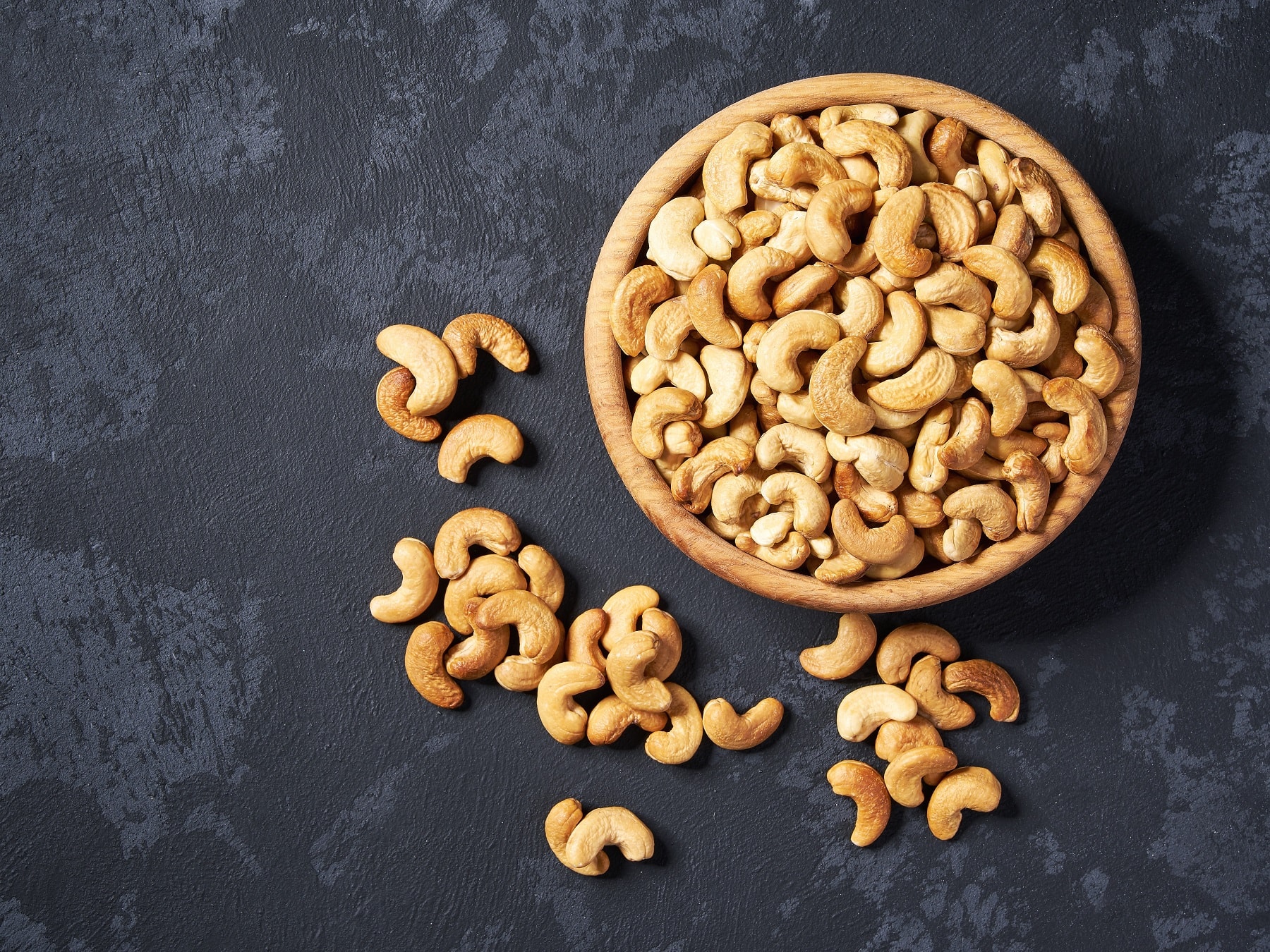 Cashewkerne auf schwarzem Untergrund von oben fotografiert.