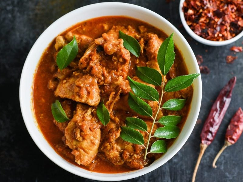 Ein tiefer Teller mit Chicken Madras auf einem dunklen Tisch.