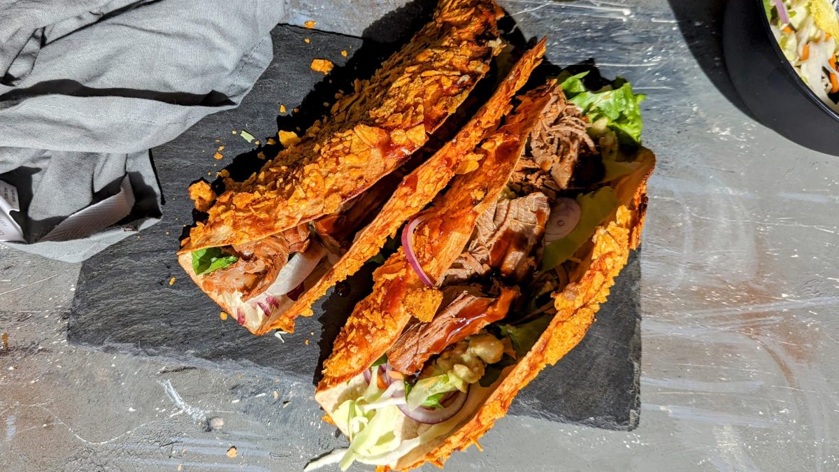 Zwei Nacho-Wraps auf einer Schieferplatte mit grauem Tisch und grauer Tischdecke.