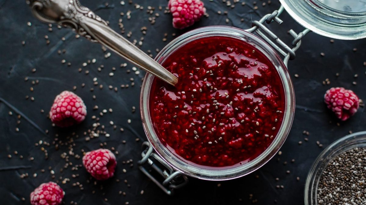 Ein Weckglas mit Himbeer-Chia-Marmelade auf einem dunklen Untergrund.
