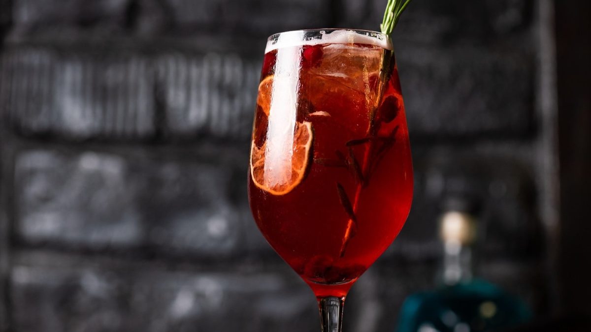 Ein Glas Lillet Rouge Tonic vor einer Steinwand.