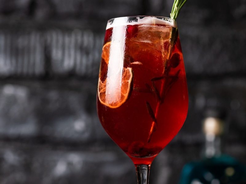 Ein Glas Lillet Rouge Tonic vor einer Steinwand.