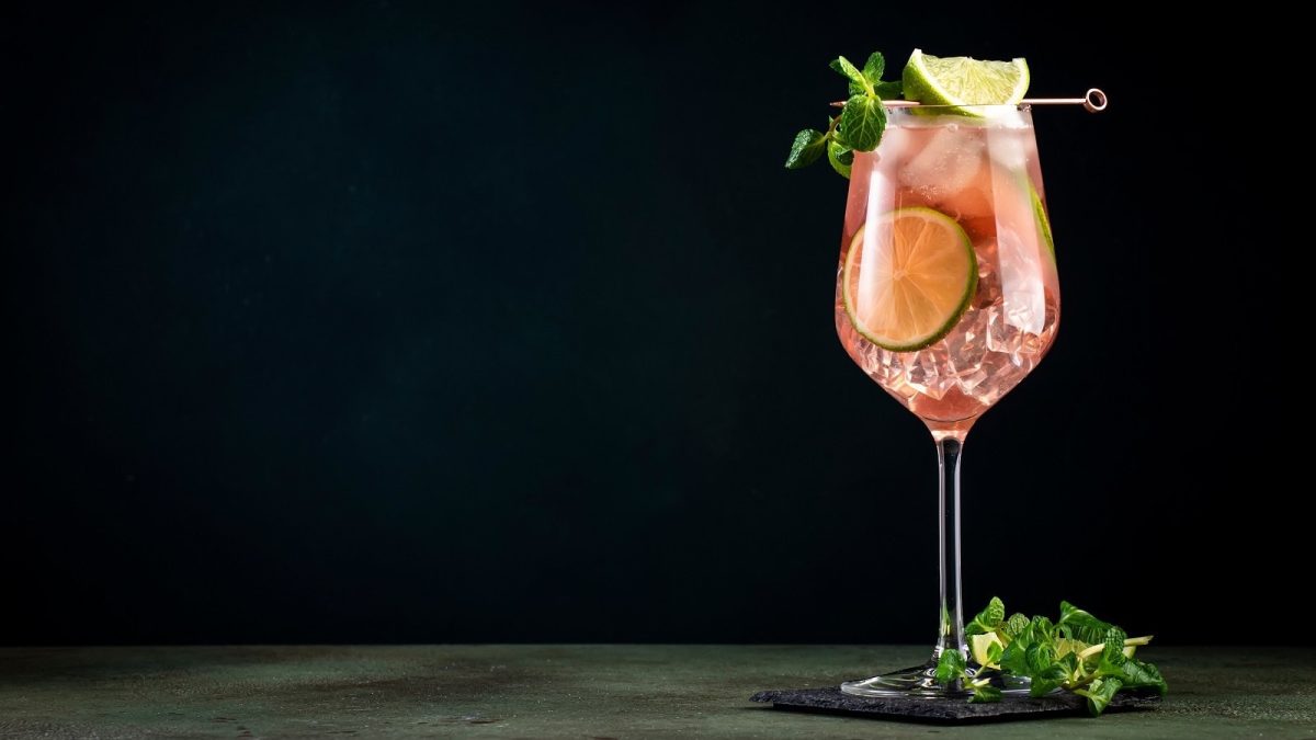 Ein Glas mit Spicy Aperol vor einem dunklen Hintergrund.