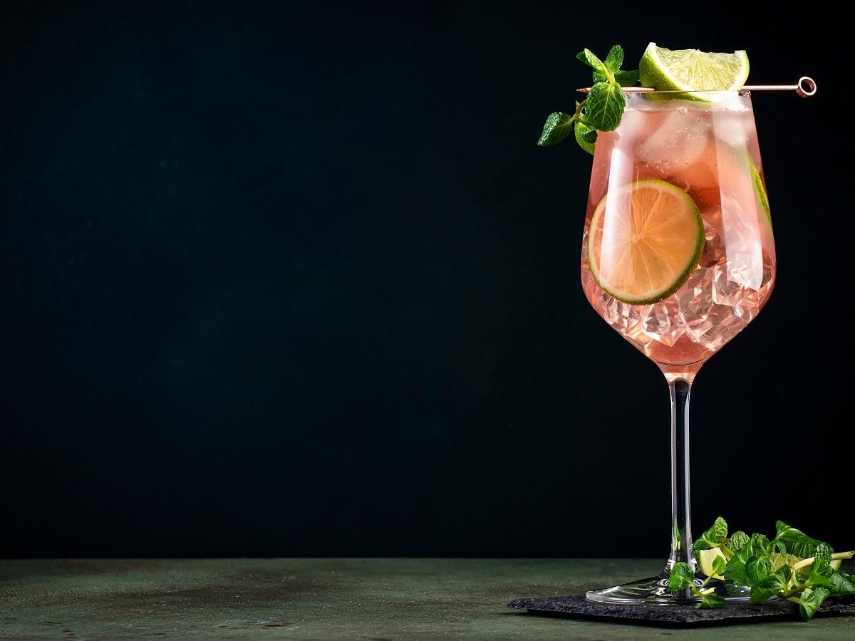 Ein Glas mit Spicy Aperol vor einem dunklen Hintergrund.