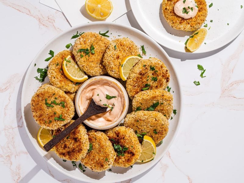 Mehrere vegane Crabcakes auf einem weißen Marmortisch von oben fotografiert.
