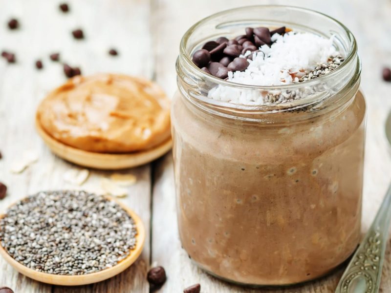 Ein Weckglas mit Cookie Dough Overnight Oats auf einem hellen Holztisch.