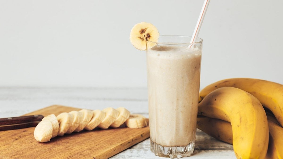 Ein Glas mit koreanischer Bananenmilch neben frischen Bananen.