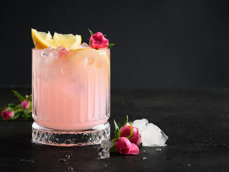 Ein Glas Lemon Sarti Spritz vor einem schwarzen Hintergrund.