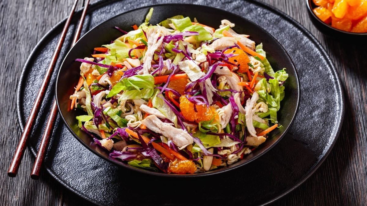 Der asiatische Kohlsalat auf einem schwarzen Teller und schwarzem Tisch von schräg oben fotografiert.