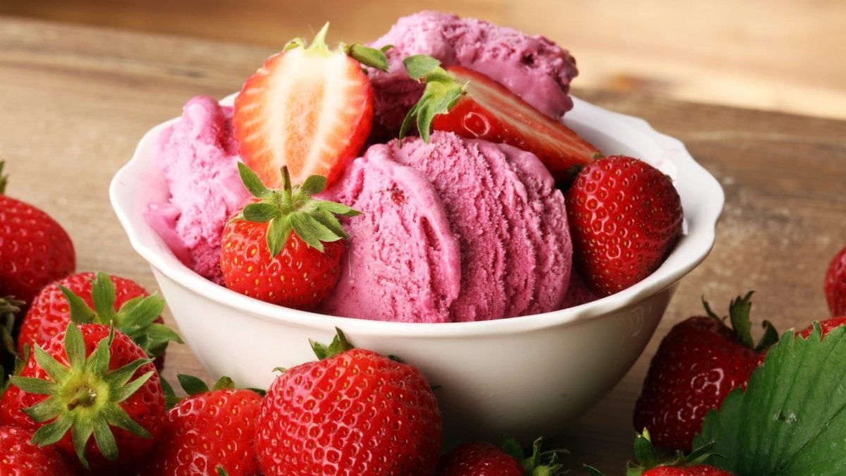 Draufsicht schräg: eine Schale Milchmädchen-Erdbeereis ohne Eismaschine. Daneben liegen frische Erdbeeren.