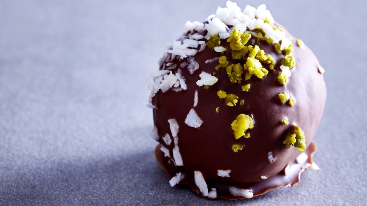 Ein Pistazien-Kokosnuss-Balls auf einem grauen Hintergrund.