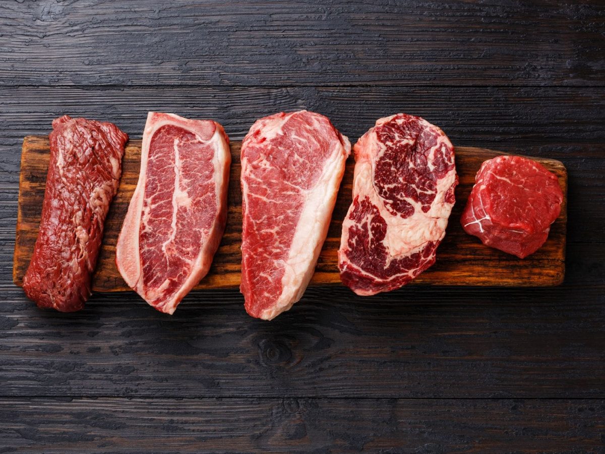 Welche Steaksorten gibt es verschiedene Steaks auf Holz und schwarzem Untergrund. Draufsicht.