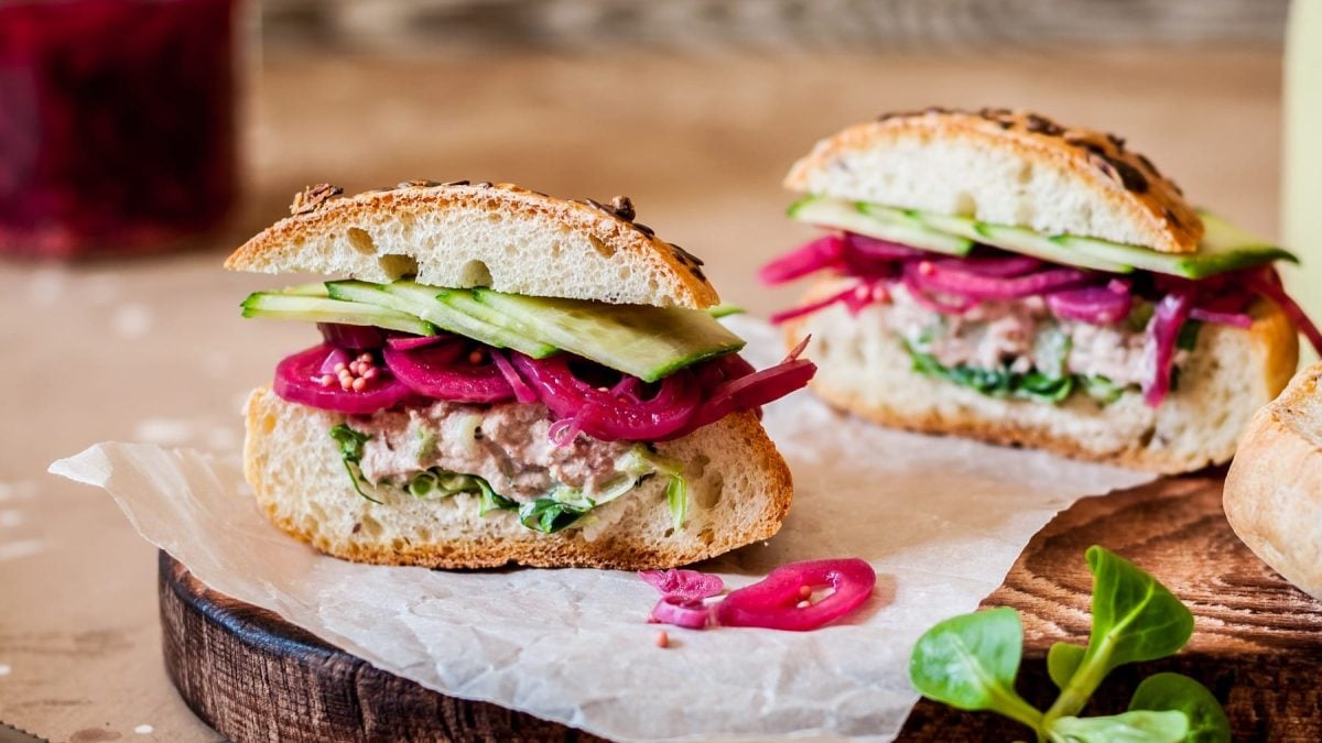 Ein halbiertes Brötchen mit Gurke, Thunfisch und roten Zwiebeln.