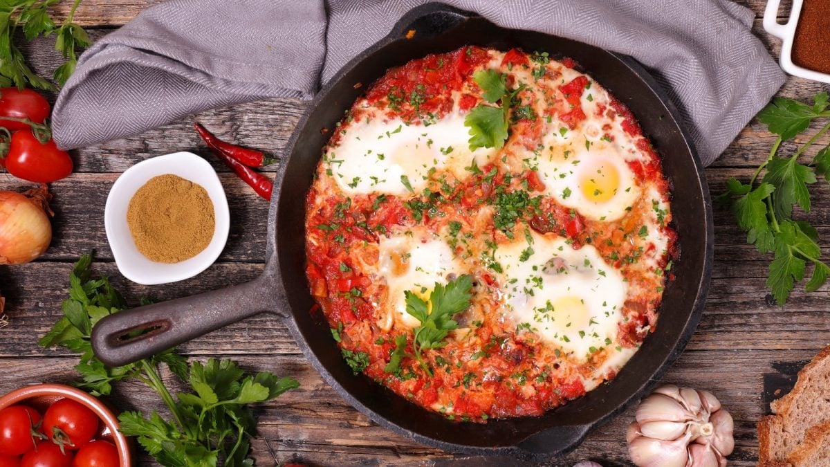 Eine schwarze gusseiserne Pfanne mit koreanischem Shakshuka auf einem Holztisch.
