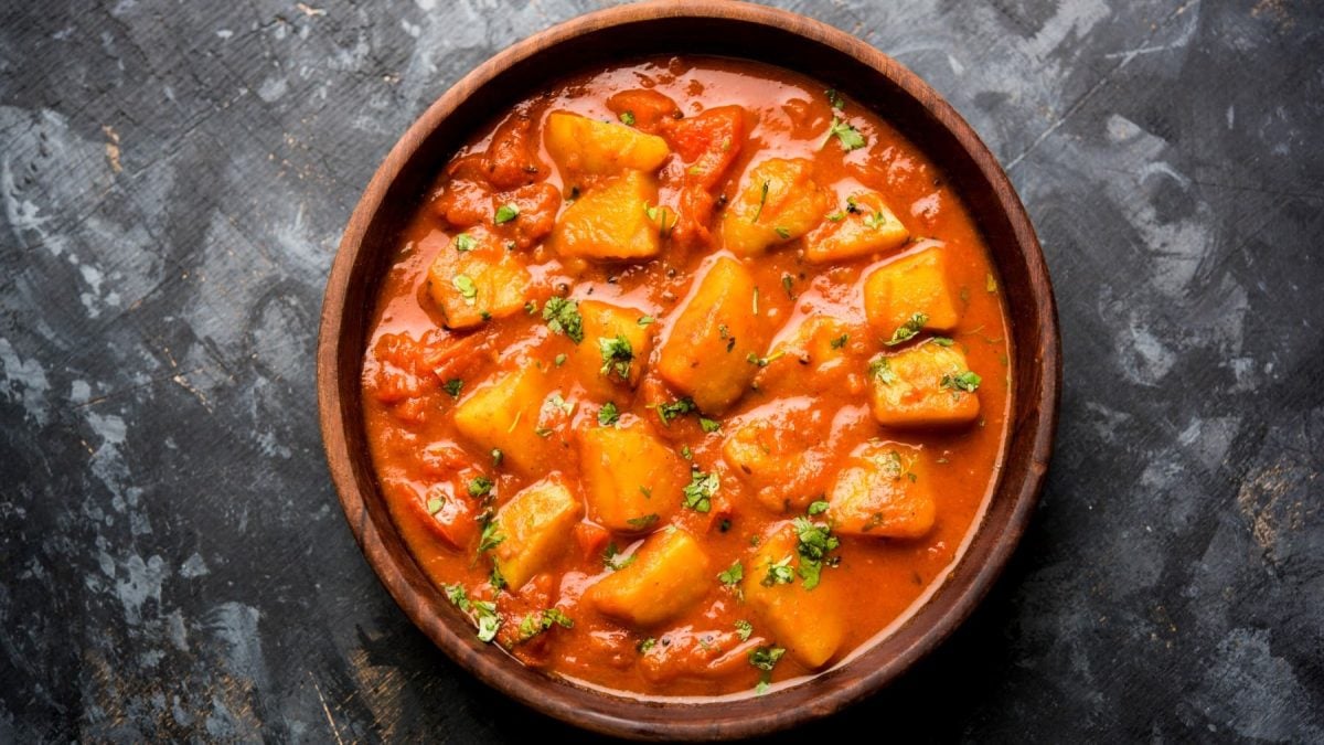 Aloo Madras in einer braunen Schüssel auf einem dunkelgrauen Hintergrund.