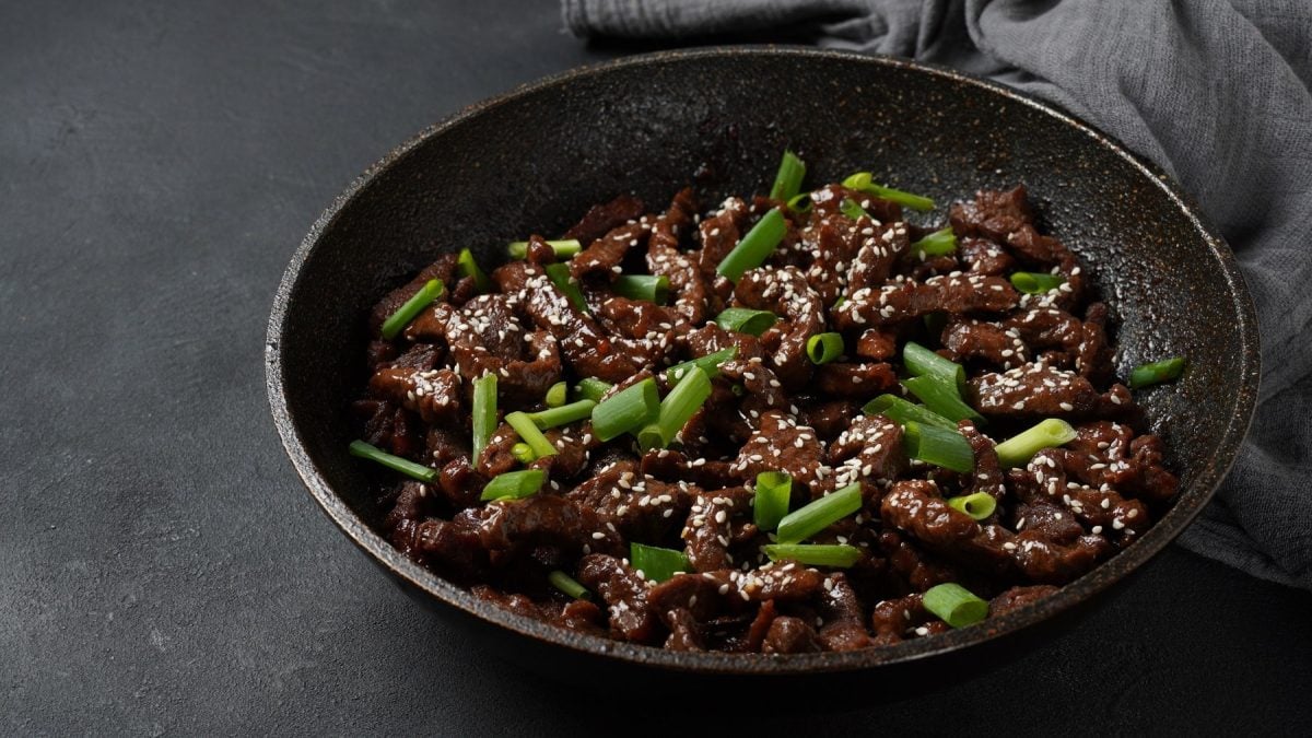 Eine schwarze Pfanne mit dem Rindfleisch in dunkler Sauce.