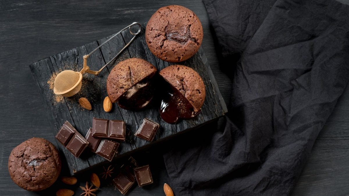 Schokokuchen mit flüssigem Kern auf dunklem Untergrund. Daneben ein schwarzes Tuch.