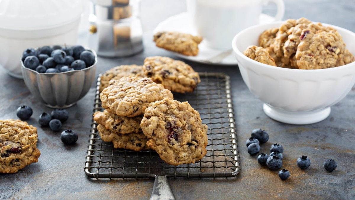 Ein Stapel mit Blaubeer-Hafer-Cookies auf einem schwarzen Gitter.