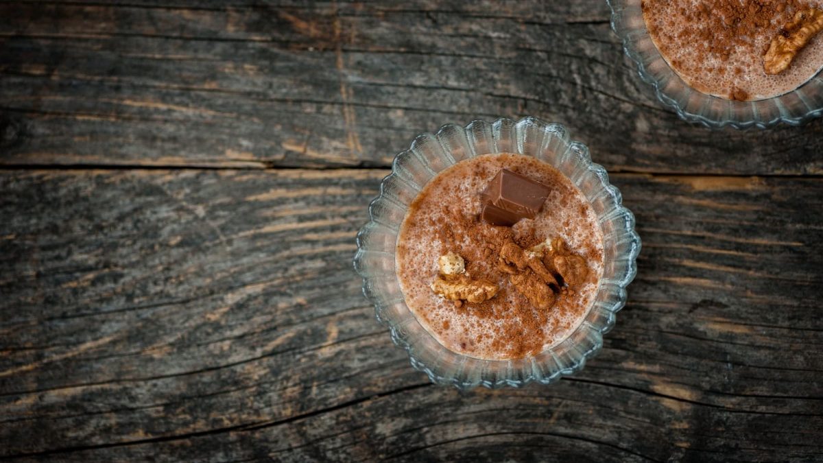 Ein Dessertglas mit einer Portion Biscoff-Pudding auf einem Holztisch.