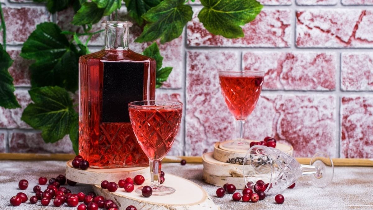 Zwei Gläser und eine Flasche aus Glas mit Cranberry-Likör.